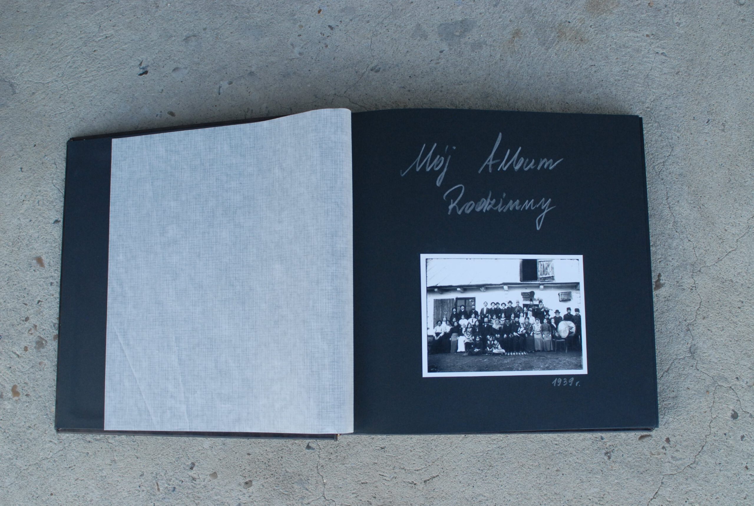 Zdjęcie pierwszej strony książki z ręcznym napisem Mój Album Rodzinny i wklejonym zdjęciem grupy osób