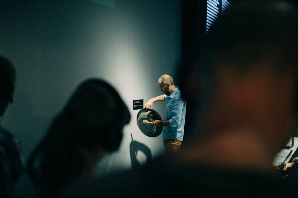 Mężczyzna stoi przy ścianie, w ręku trzyma okrągły kształt