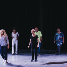 Grupa ośmiu starszych osób w tańcu w sali teatralnej