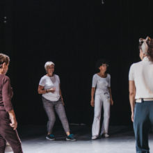 Pięć kobiet stojących luźno w sali teatralnej