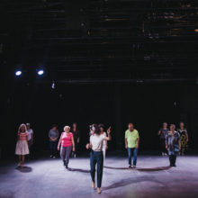 Grupa osób tańczy w sali teatralnej