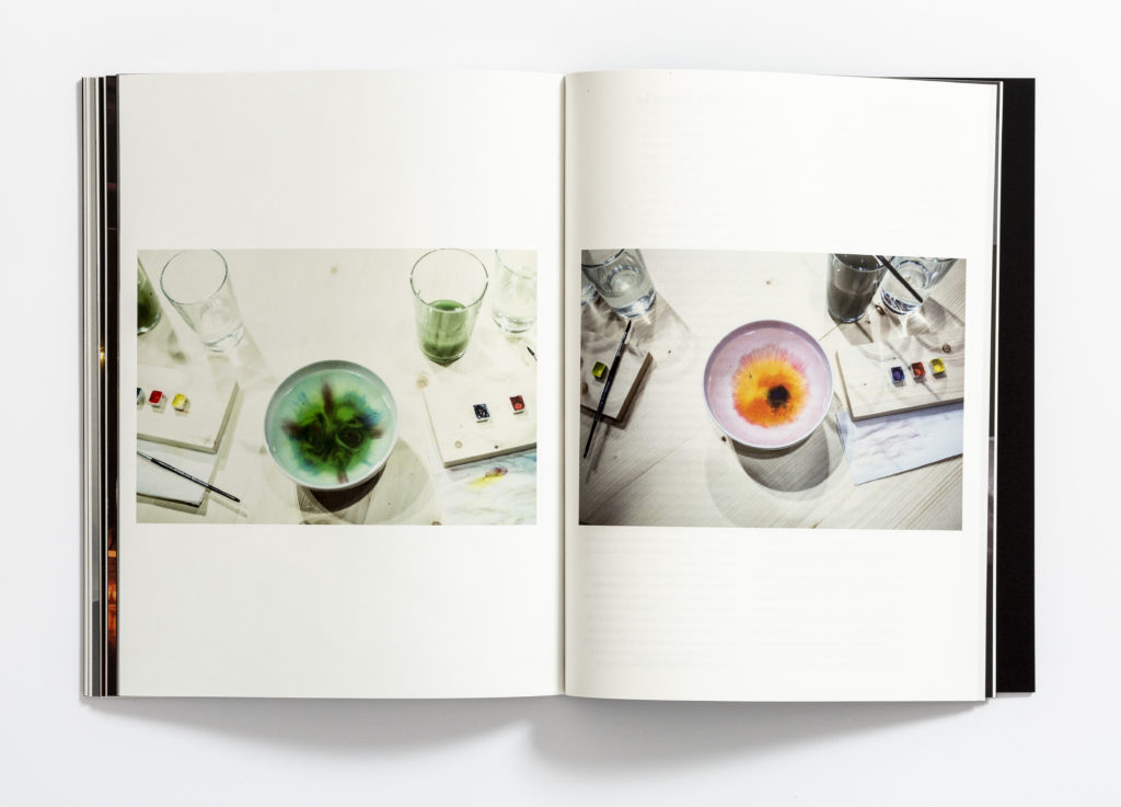 [Zdjęcie dwóch stron książki "Zapraszanie. Sarkis-Kantor". Na zdjęciu widać miseczki i szklanki z wodą, kolorowe farbki oraz pędzelki.]