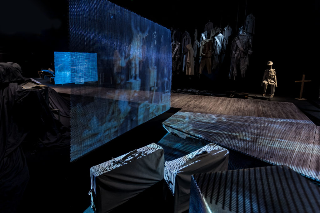 [AD: Na zdjęciu fragment rampy dla zwiedzających oraz cześć ekspozycji stałej: niebieski ekran z projekcją, na pierwszym planie walizki.