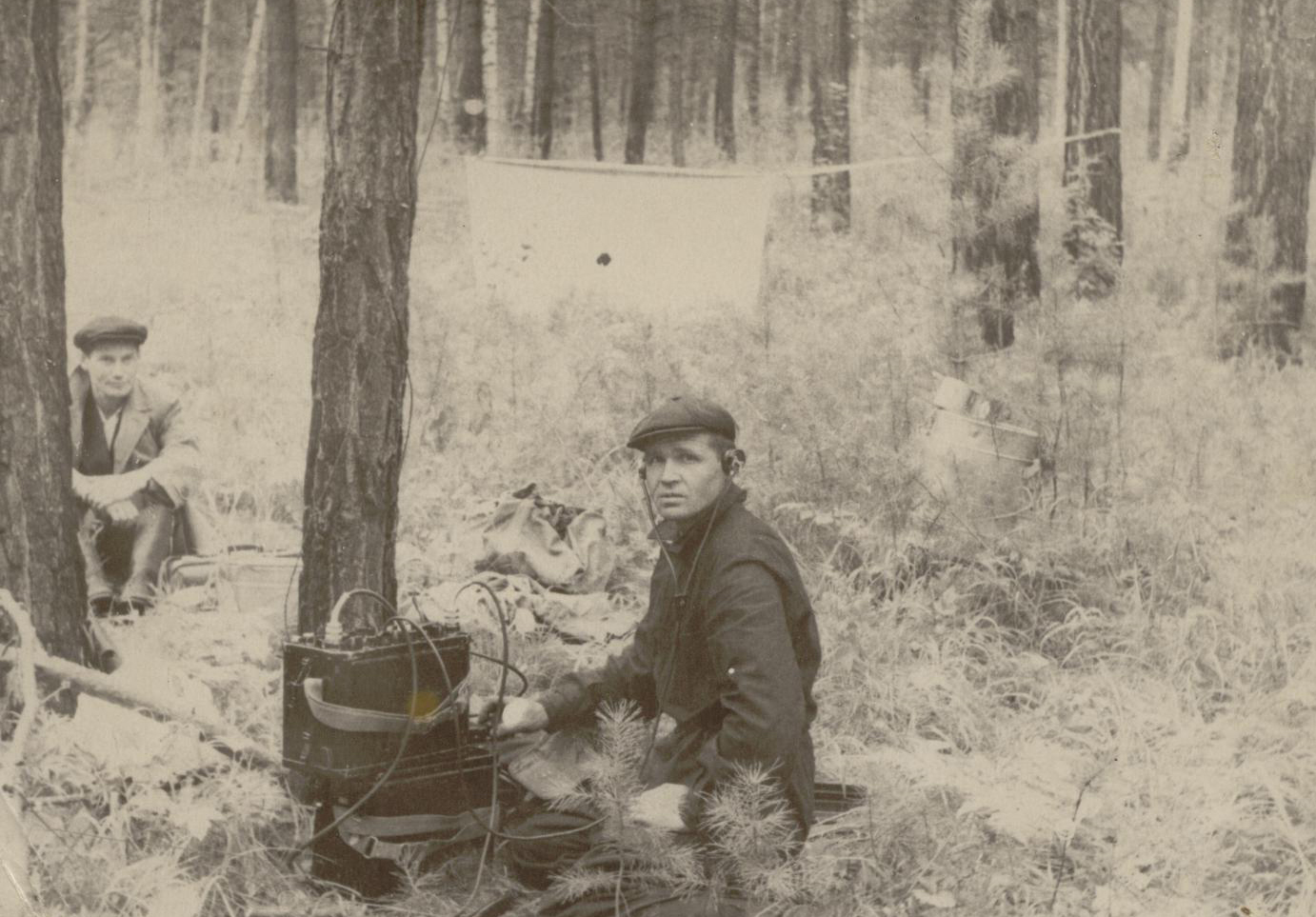 Archival photo; man sitting in the forest, looking at the photographer