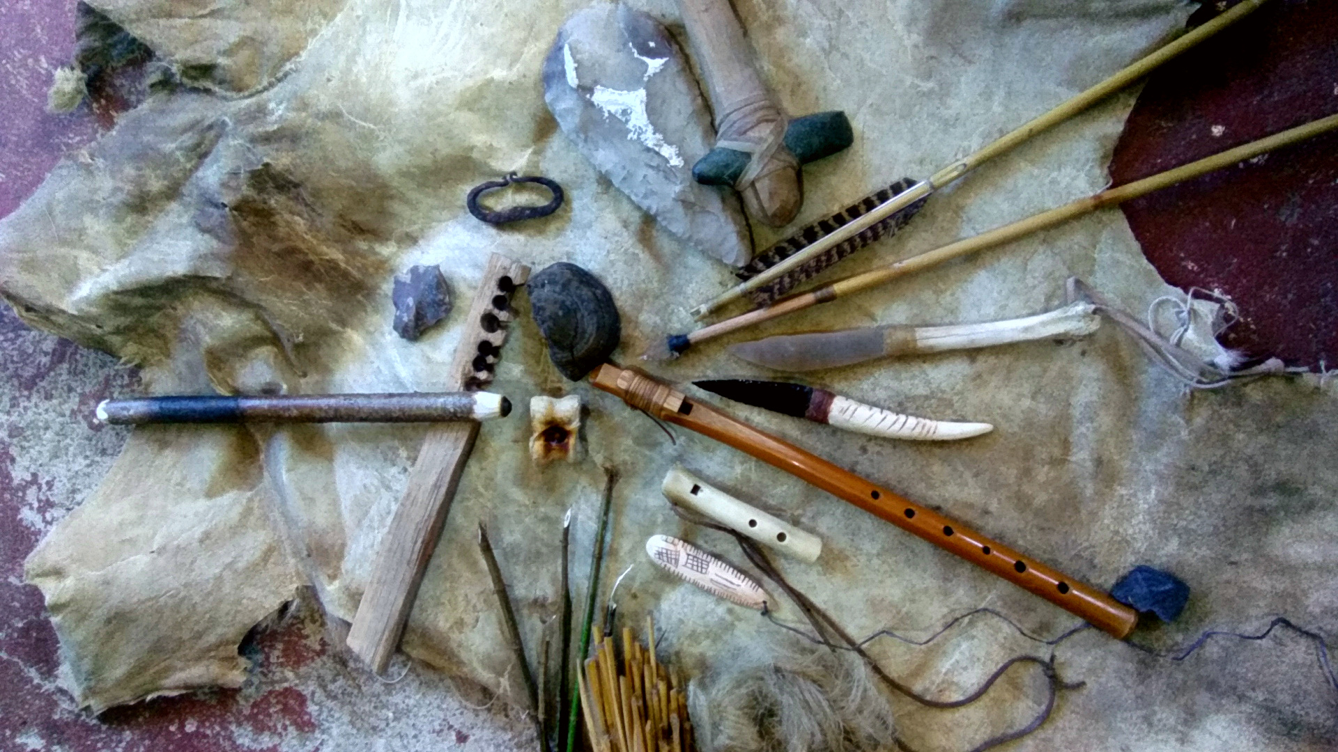 Na zwierzęcej skórze leżą proste drewniane instrumenty i kamienne narzędzia