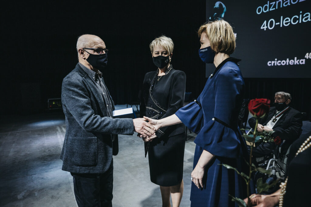 Zdjęcie przedstawia trzy osoby. Na pierwszym planie Monika Gubała podaje dłoń Romanowi Siwulakowi. Za nimi stoi Iwona Gibas.