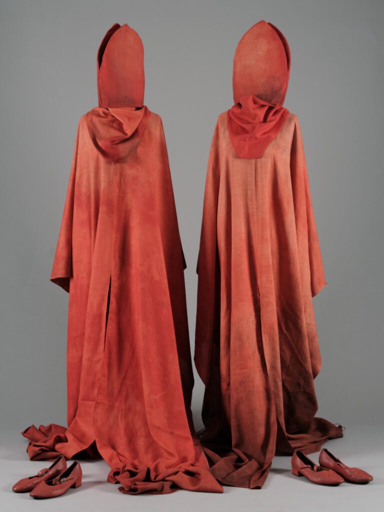 Dwa czerwone kostiumy, składające się z czerwonych biskupich szat, butów i wysokiej mitry.