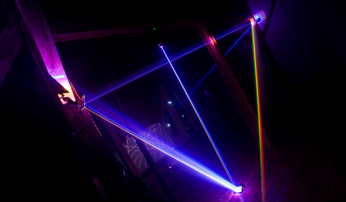 Zdjęcie wnętrza pomieszczenia, oświetlonego przypominającymi lasery światłami. Wystawa w Galerii-Pracowni Tadeusza Kantora