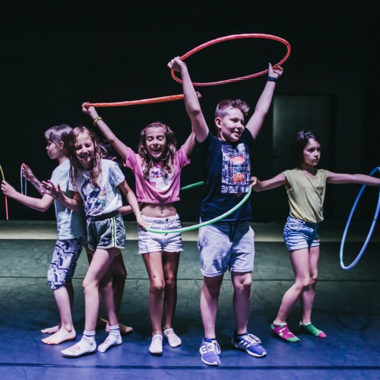 Fotografia przedstawia grupę dzieci bawiącej się kołami hula-hop