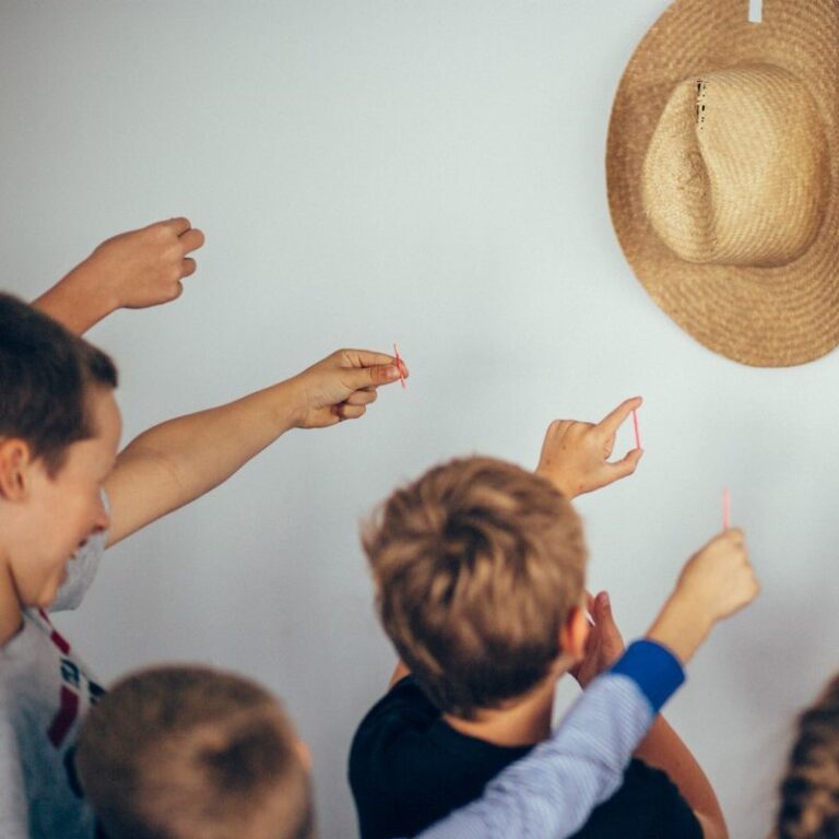 Na zdjęciu widzimy grupę dzieci wyciągającą ręce w stronę kapelusza